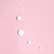 Weiße Tropfen auf rosa Untergrund.
