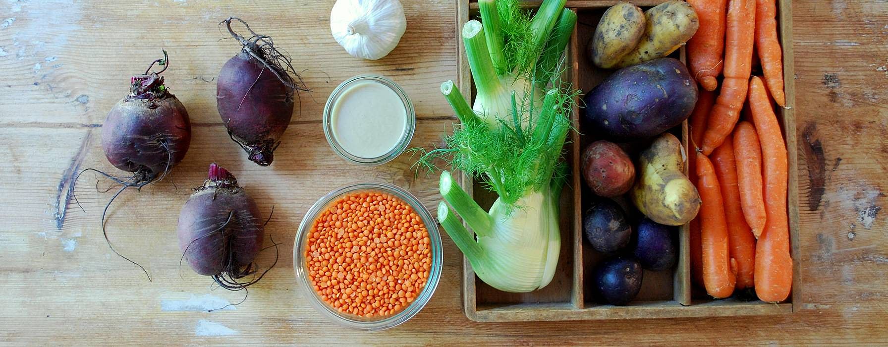 Auf einem Tisch liegen Fenchel, Karotten, Linsen und andere Zutaten fuer das Gericht