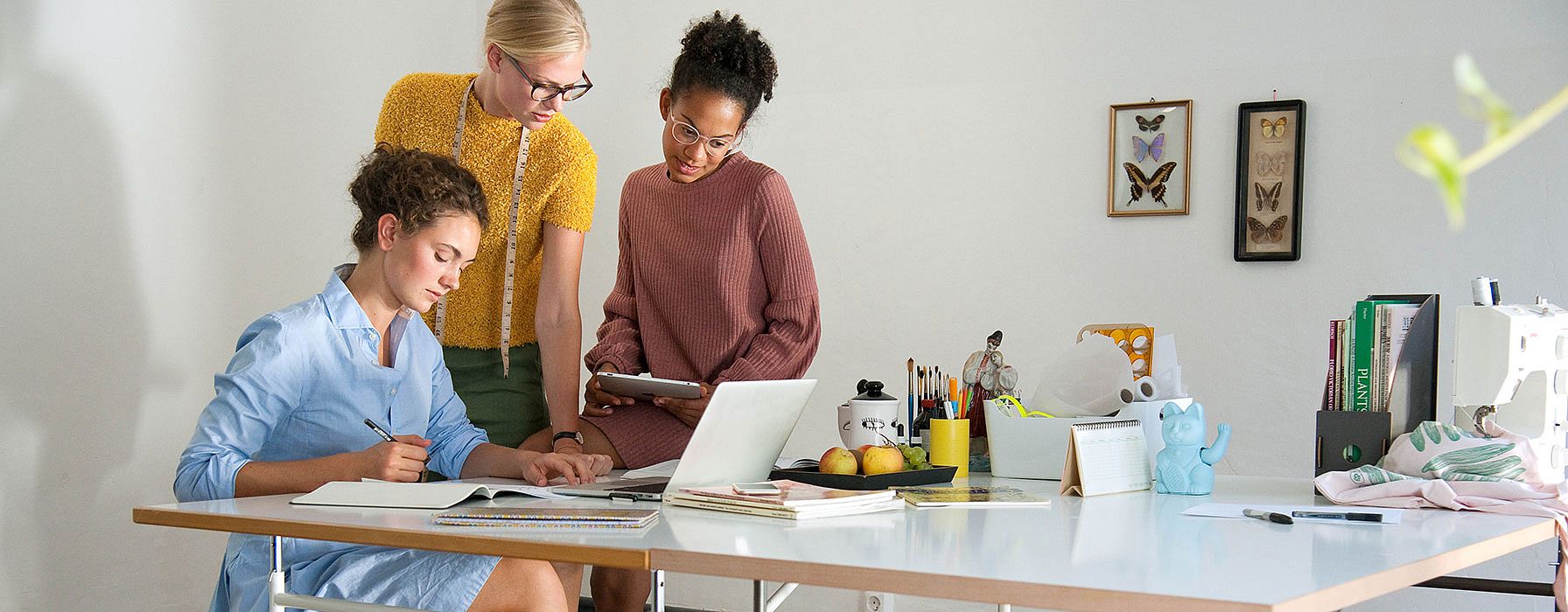 Drei Frauen im Buero am Schreibtisch vor dem Laptop