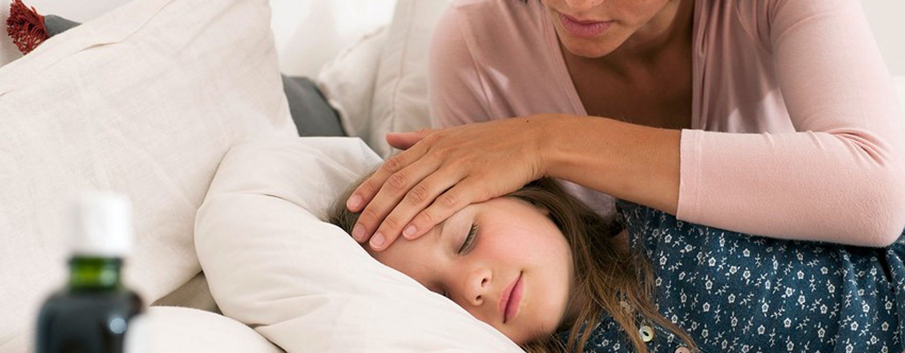 Mama legt schlafendem Kind die Hand auf die Stirn