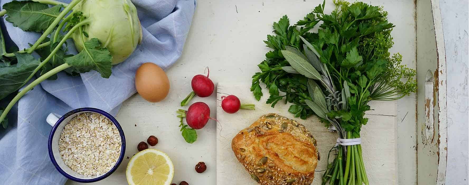 Auf einem Tablett liegen ein Broetchen, ein Ei, Kohlrabi und Kraeuter als Zutaten fuer den Burger