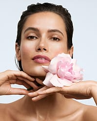 Woman with rose by face