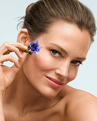 Woman holding flower by face