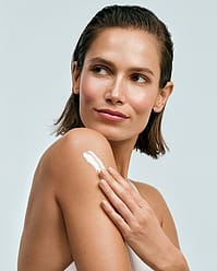 Woman applying body moisturiser