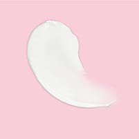 La texture blanche du soin de jour lissant Weleda sur fond rose