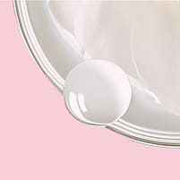 La crème blanche du soin de nuit lissant Weleda dans une boîte sur fond rose