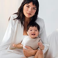 Mother holding smiling baby sitting down