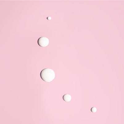 Weiße Tropfen auf rosa Untergrund.