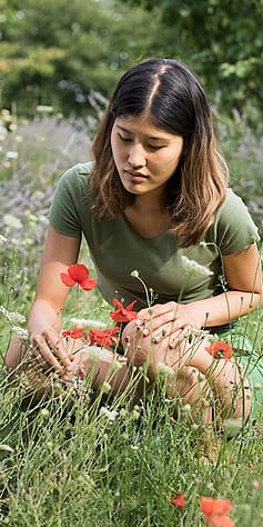 woman bending in field to pick flowers