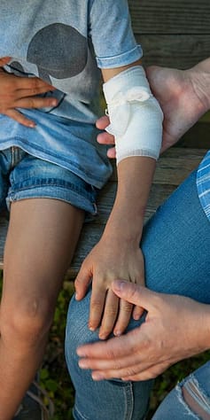 Woman holding a childs arm that has been bandaged.