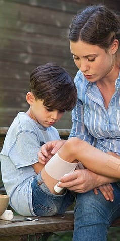 Woman bandaging child's leg.