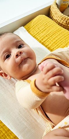 Baby on change table smiling dressed in yellow