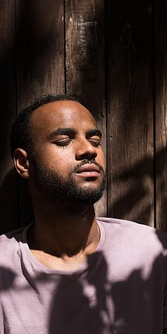L'homme est assis les yeux fermés au soleil