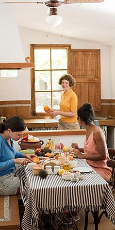 Three women preparing healthy food in a kitchen.