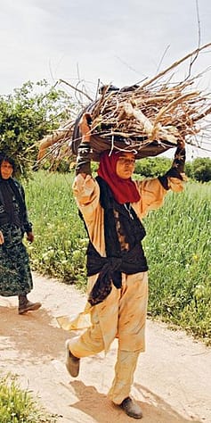 woman walking with sticks on their heads