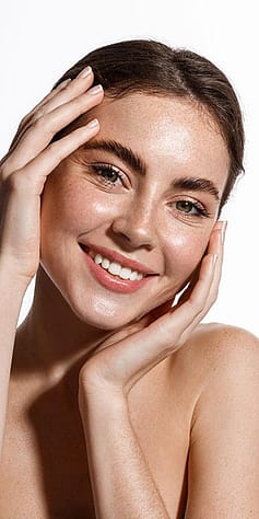 Frau umfasst ihr Gesicht mit beiden Haenden