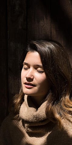 Frau sitzt mit geschlossenen Augen in der Sonne