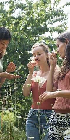 Un gruppo di ragazze all'aperto annusa delle bacche viola in mezzo ai fiori