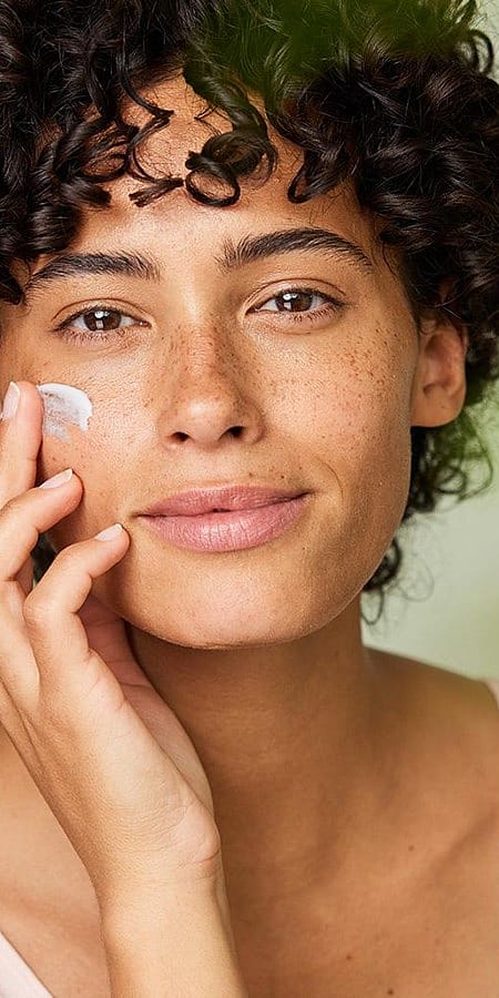 Junge Frau trägt Gesichtscreme auf