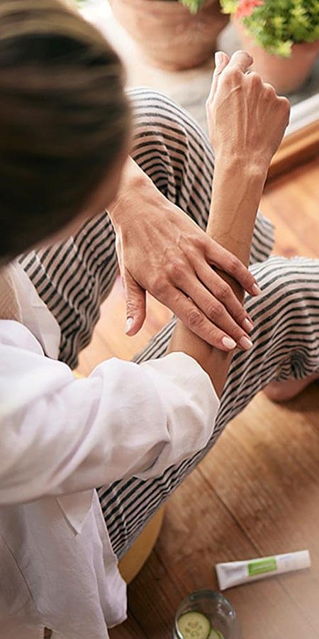 Frau traegt kuehlendes Gel auf ihren Unterarm auf