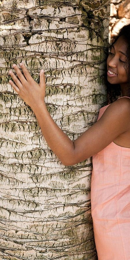 Jeune femme touche le tronc d'un arbre