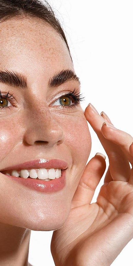 Frau beruehrt mit den Fingerspitzen ihre Wange