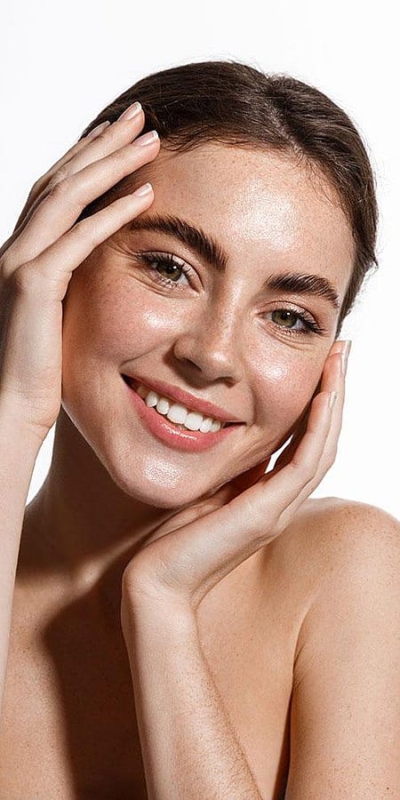 Laechelnde Frau haelt ihr Gesicht in den Haenden