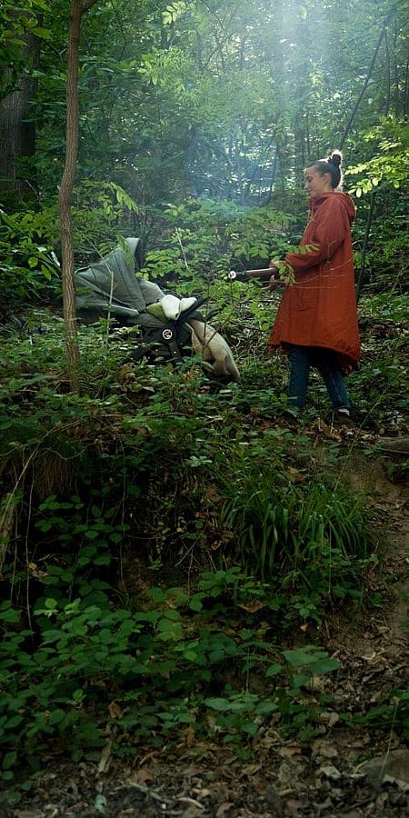 Donna con passeggino in un bosco