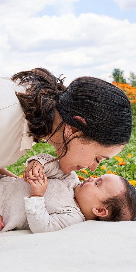 Mamma sorride e tocca il nasino del figlio neonato con il suo
