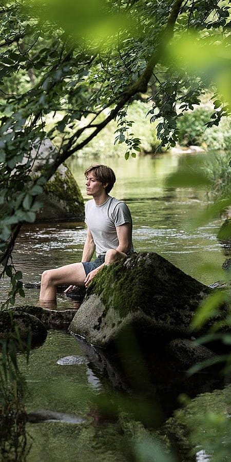 Homme au bord de la rivière entouré de forêt