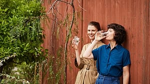 Women drinking water leaning on a wall.