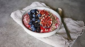 Bowl mit Muesli garniert mit frischen Brombeeren, Heidelbeeren, Feigen und Saaten