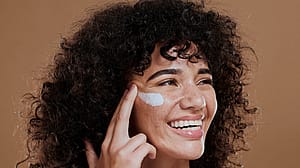 Donna riccia e mora che applica la crema sul viso