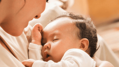 mujer sosteniendo a un bebé dormido en los brazos