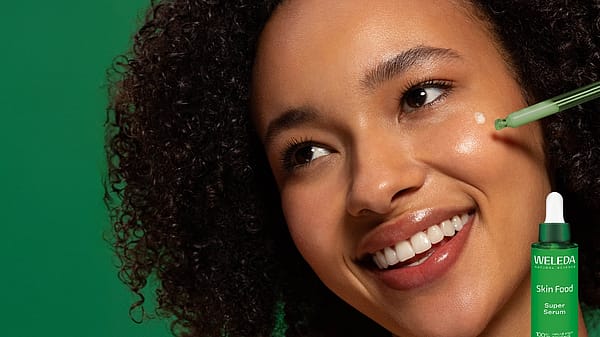 Kvinna smörjer in ansiktet med Weleda Skin Food