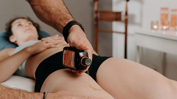 sportive se faisant masser par un kiné avec huile de massage arnica