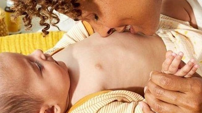 Moeder geeft een kus op het buikje van haar baby