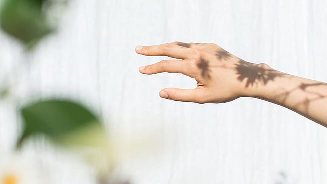 Spiel von Licht und Schatten auf der Hand einer Frau
