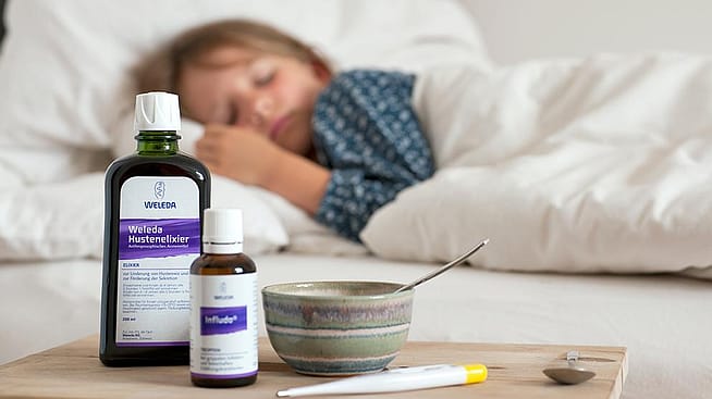 Un enfant malade dort. Produits de soins personnels Weleda au premier plan