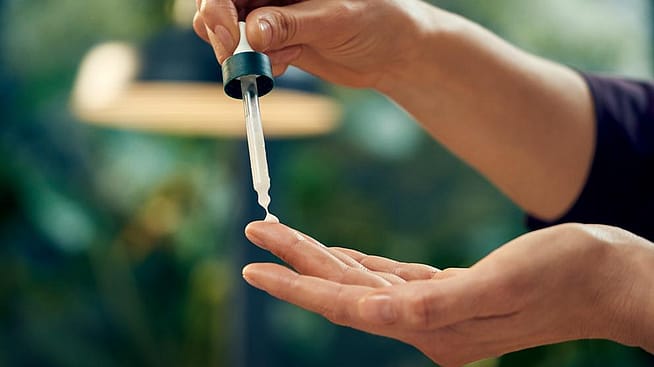 Une femme met quelques gouttes de sérum sur ses mains