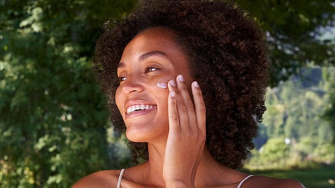 Vrouw smeer Skin Food Voedende Nachtcrème op haar wang