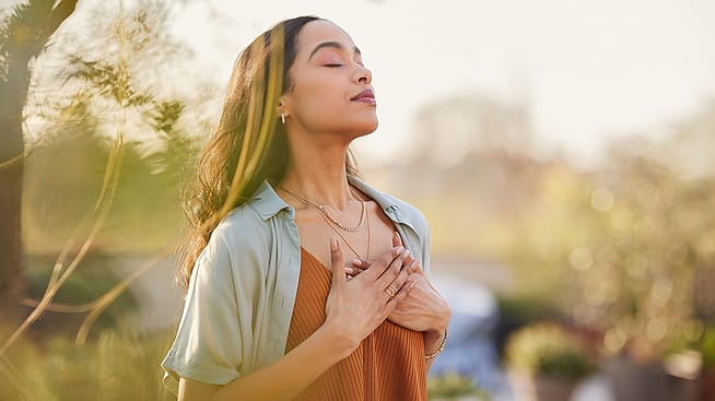 Frau mit geschlossenen Augen und Goldschmuck in der Sonne