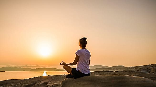 Frau macht Yoga in der freien Natur beim Sonnenuntergang