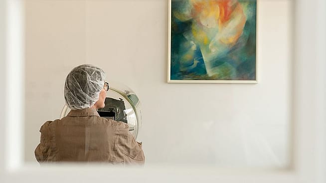 Eine Person betrachtet ein Bild an der Wand