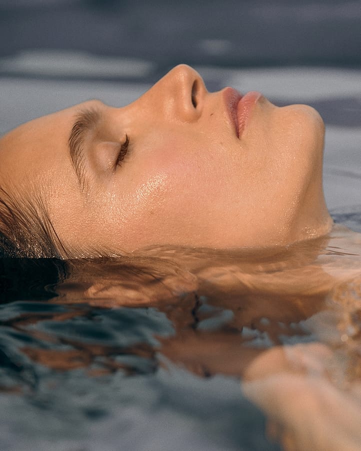 Frau liegt im Wasser, nur das Gesicht ist zu sehen