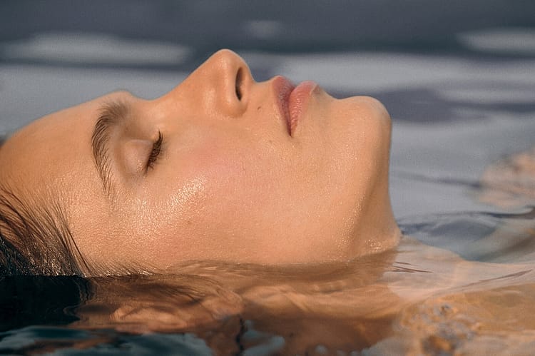 Frau liegt im Wasser, nur das Gesicht ist zu sehen