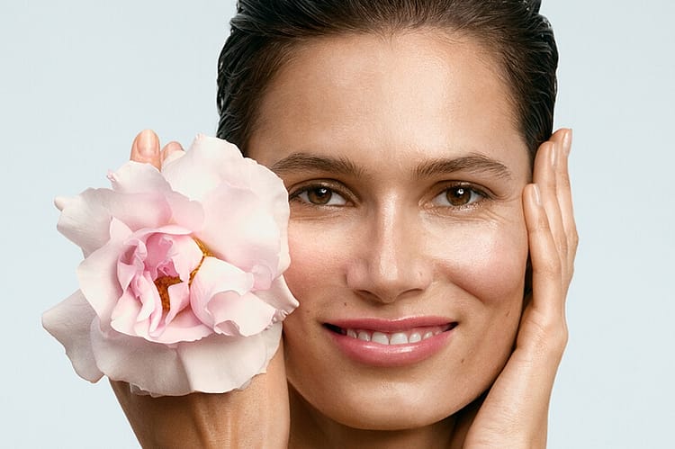 Gesicht einer Frau mit der Blüte einer Wildrose an ihrem Gesicht