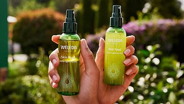 dos manos agarrando dos botes de aceite seco skin food