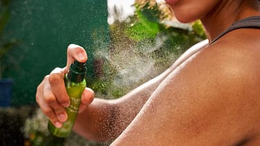 Kvinna sprayar Weleda Skinfood dry oil på kroppen