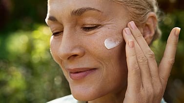 woman applying cream on face